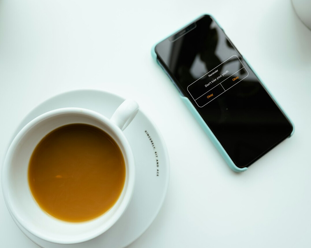 Smartphone displaying a newsletter email next to a cup of coffee